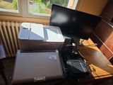 a laptop and a printer sitting on a desk in front of a window