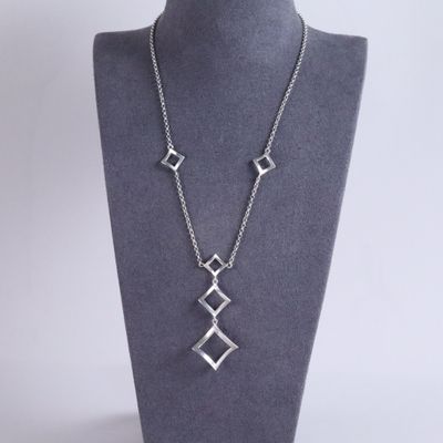 a silver necklace with three squares on a mannequin neck