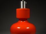 an orange vase with a silver top on a gray surface