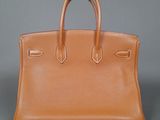 a brown leather handbag on a gray background