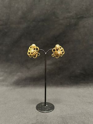 a pair of gold earrings on a black stand