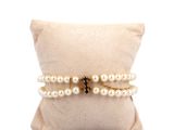 two white pearls and a black diamond bracelet on a pillow