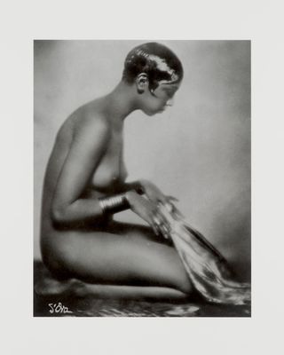 an old black and white photo of a naked woman sitting on the ground