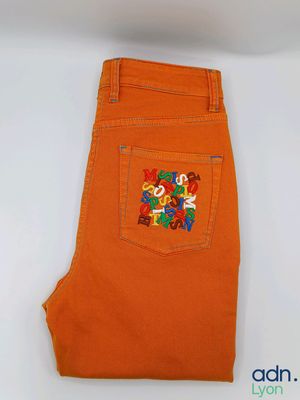 a close up of a pair of orange jeans on a white surface