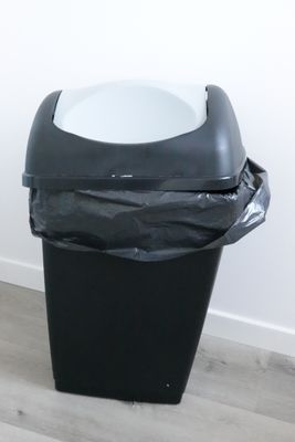 a black trash can with a white bowl in it