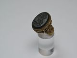 une image représentant une bague sur laquelle est posée une pièce de monnaie romaine