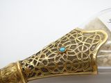 une bouteille en verre avec une poignée dorée et une pierre turquoise à l'intérieur