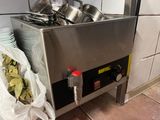 Des casseroles et des poêles sont empilées sur une cuisinière dans une cuisine.
