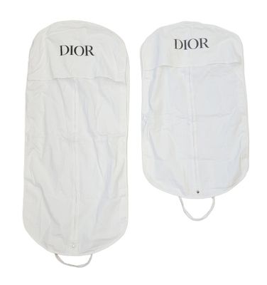 deux housses à vêtements blanches sur lesquelles sont inscrits les mots « Dior » et « Dior »