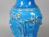 un vase bleu posé sur une table, sur fond gris