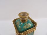 an image of a green and gold perfume bottle on a white surface
