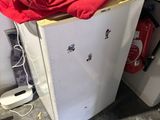 a small white refrigerator with a red shirt on top of it