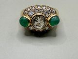 a close up of a diamond and emerald ring on a table