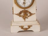 a white and gold clock sitting on top of a table