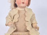 an image of a doll sitting on the ground wearing a dress and hat
