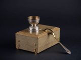 a silver cup and spoon sitting on a wooden box
