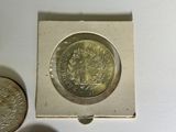 a silver coin sitting next to a silver coin on a white surface