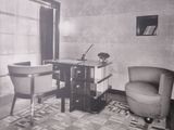 a black and white photo of a desk and chair in a room