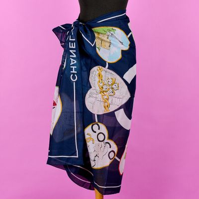 une femme portant un haut noir et une jupe bleue, avec un foulard Chanel