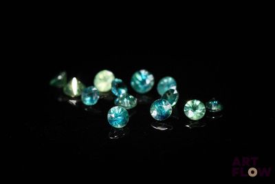 un gros plan sur un ensemble de diamants bleus et verts posés sur une surface noire