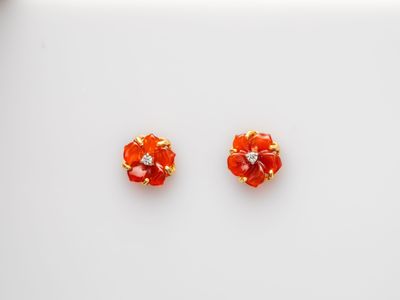 a pair of red and gold earrings on a white surface