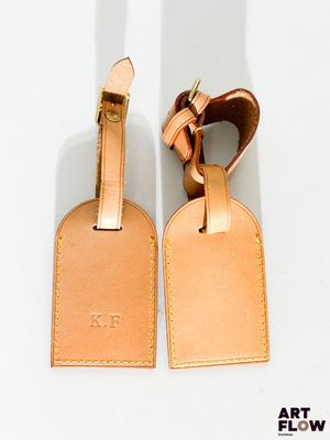 une paire d'étiquettes à bagages en cuir beige sur un fond blanc