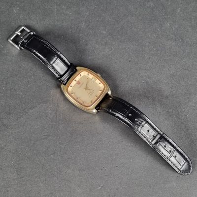 a close up of a watch on a table with a black strap