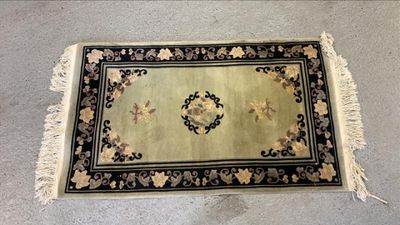 une photo d'un tapis posé au sol, bordé d'une frange noire