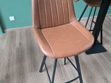 un tabouret de bar en cuir marron avec un piètement en métal noir