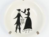 a black and white plate with a drawing of a man and a woman holding a bird cage
