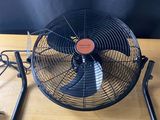 un ventilateur électrique posé sur une table en bois près d'un mur