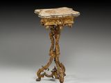 une petite table avec un plateau en marbre, posée sur un piètement