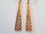 a pair of gold tone earrings on a white surface