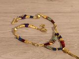 a long necklace with a gold chain and a colorful bead on it