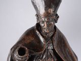 statue d'un homme coiffé d'un chapeau et vêtu d'une robe, tenant un chien dans ses bras