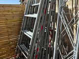 a pile of metal scaffolding leaning against a wooden fence