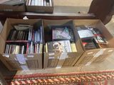 many boxes of dvds sitting on a rug on the floor