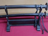 two samurai swords on a stand on a red cloth