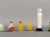 Plusieurs bouteilles en verre et figurines sont alignées sur une surface grise