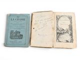 two old books are sitting on a white surface one is open and the other has a drawing of a castle