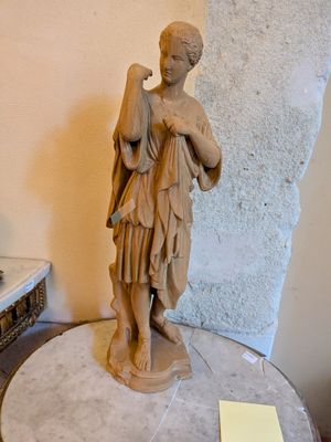 une statue représentant une femme tenant un sac posé sur une table