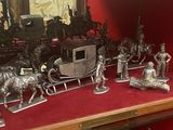 figurines en argent représentant des chevaux, des calèches et des attelages sur un fond rouge