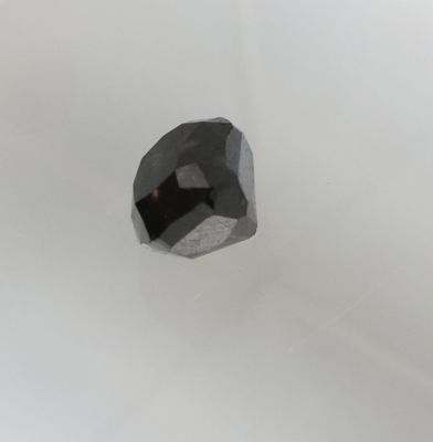 un gros plan d'un diamant noir sur une surface blanche