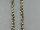 collier plaqué or avec une pièce de monnaie suspendue à une chaîne, posé sur une table