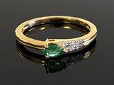 an emerald and diamond ring on a black surface with reflection