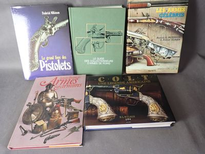 several books are sitting on a gray surface with a gun in the background
