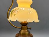une lampe à l'ancienne avec un abat-jour en verre posée sur un pied en bois
