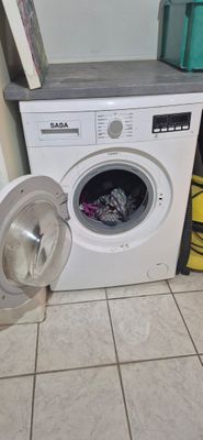 a washing machine sitting on the floor next to a trash can