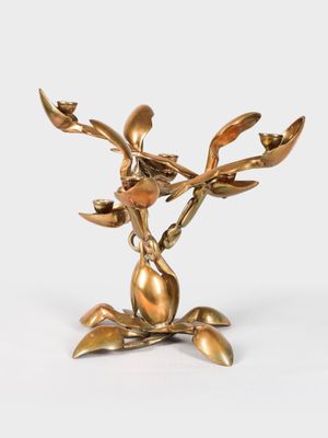 brass figurine of a flower with leaves on a white background