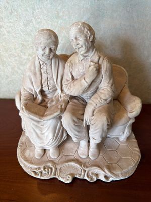 two figurines of two people sitting on a bench